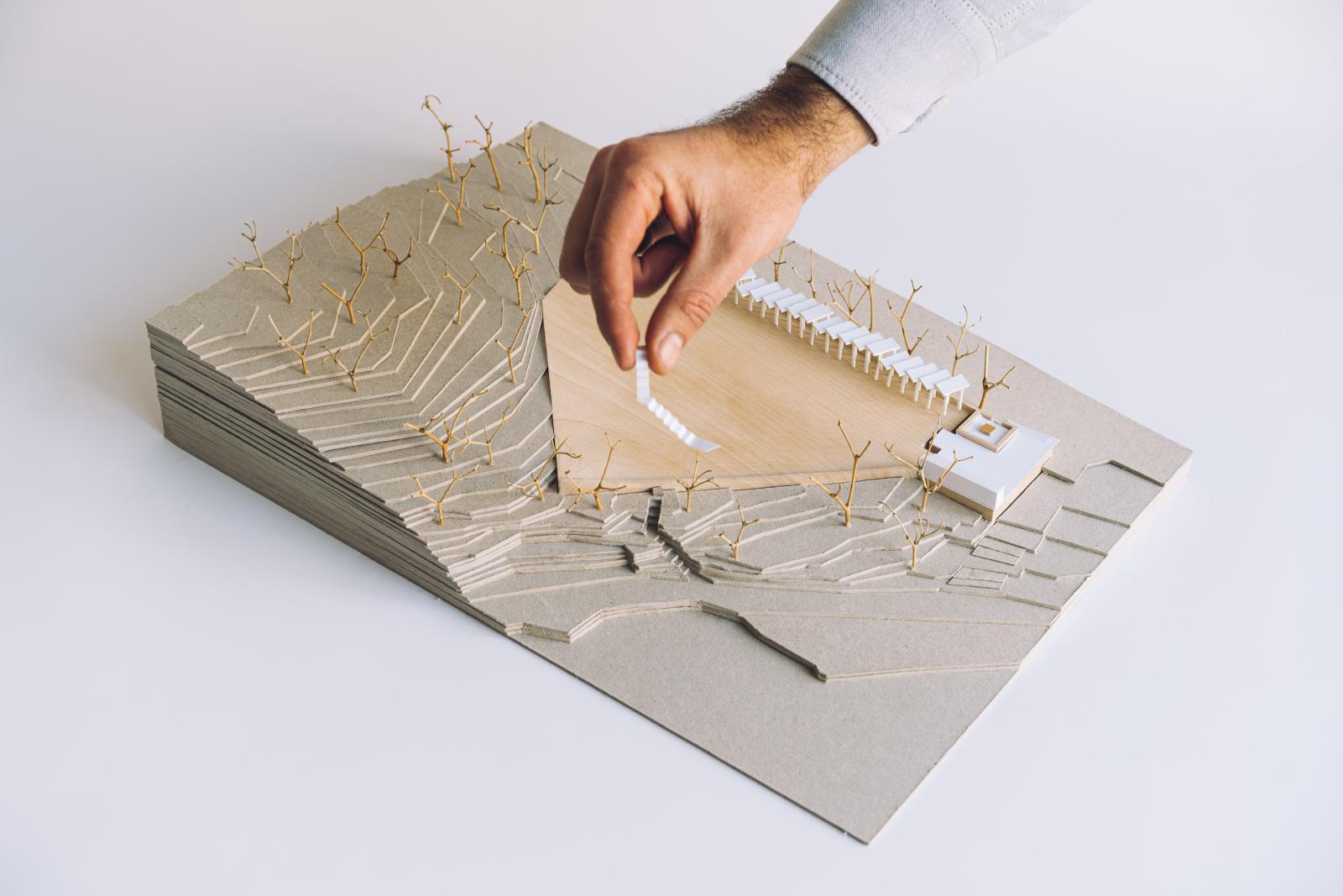Rainwater collector, 1:250

This model explores the revitalization of the Zamalin gusterna, a traditional rainwater harvesting structure originally built on the village periphery, now repurposed as a vibrant urban catalyst within a dense residential fabric. The model's primary purpose was to test the spatial transition of the site from an underutilized "infrastructure void" into a multifunctional public square.

We used this model to iteratively study the relationship between the massive, sloped catchment surface and the addition of a new energy pavilion. By physicalizing the proposal, we could refine the placement of PV panels and filtration systems while ensuring the upper surface remained an open, flexible stage for community life—accommodating concerts, outdoor cinema, and exhibitions.

The model informs the viewer about the project’s dual nature: it is both a high-functioning machine for water security (supplying firefighters and local irrigation) and a social anchor. It highlights how the intervention respects the traditional scale of the site while introducing sustainable technology. Ultimately, the model demonstrates how preserving a "shizophrenic" historical context can lead to a contemporary, socially responsible public space that functions as both a utility and a heart for the community.

Paper, Cardboard, Softwood

Made by Luka Cvitan & Antonia Cvitan Vuletić
