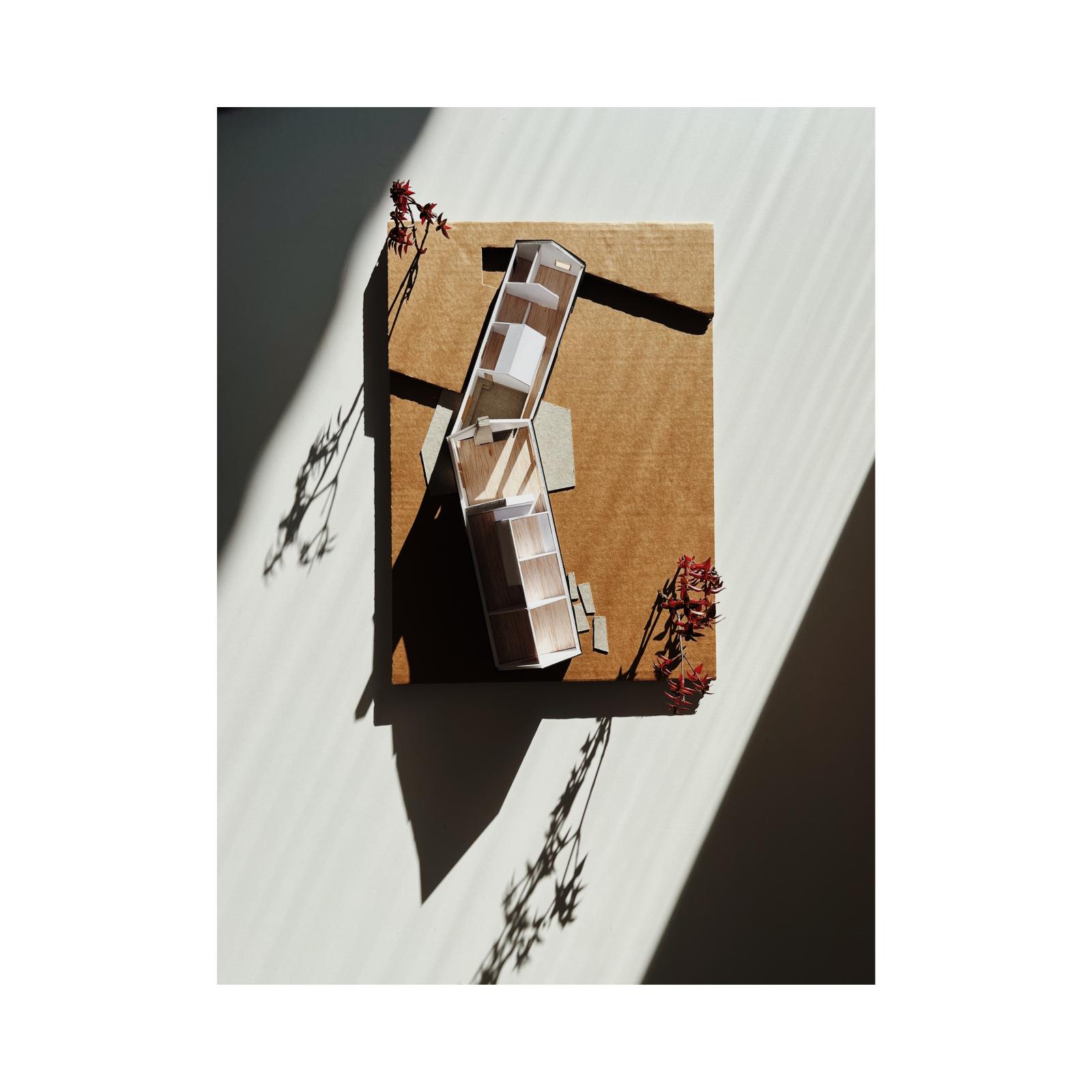 #projet_23041 Point du jour : new family house (bousval). scale : 1/100

Set at the heart of open fields, this newly built single-family house is discreetly integrated into the rural landscape and benefits from expansive views over the surrounding countryside. Its siting takes advantage of the site’s horizontality and visual openness, reinforcing the relationship between architecture and territory.

The project is organized around two distinct wings, whose volumetric composition clearly structures the domestic program. The first wing, developed over two levels, accommodates service spaces on the ground floor and the children’s bedrooms above, offering a functional and adaptable layout. The second wing, on a single level, houses the main living areas, including the living room, home office, and the primary suite, fostering a direct connection with the outdoor spaces.

Central to our methodology, the physical model allows us to explore, test, and refine spatial relationships and volumetric articulations. It translates our interpretation of the program into three-dimensional form, revealing the junction between volumes and generating shared spaces for convergence, both indoors and outdoors

Cartboard / paper / wood

Made by Louise De Kepper, Intern 