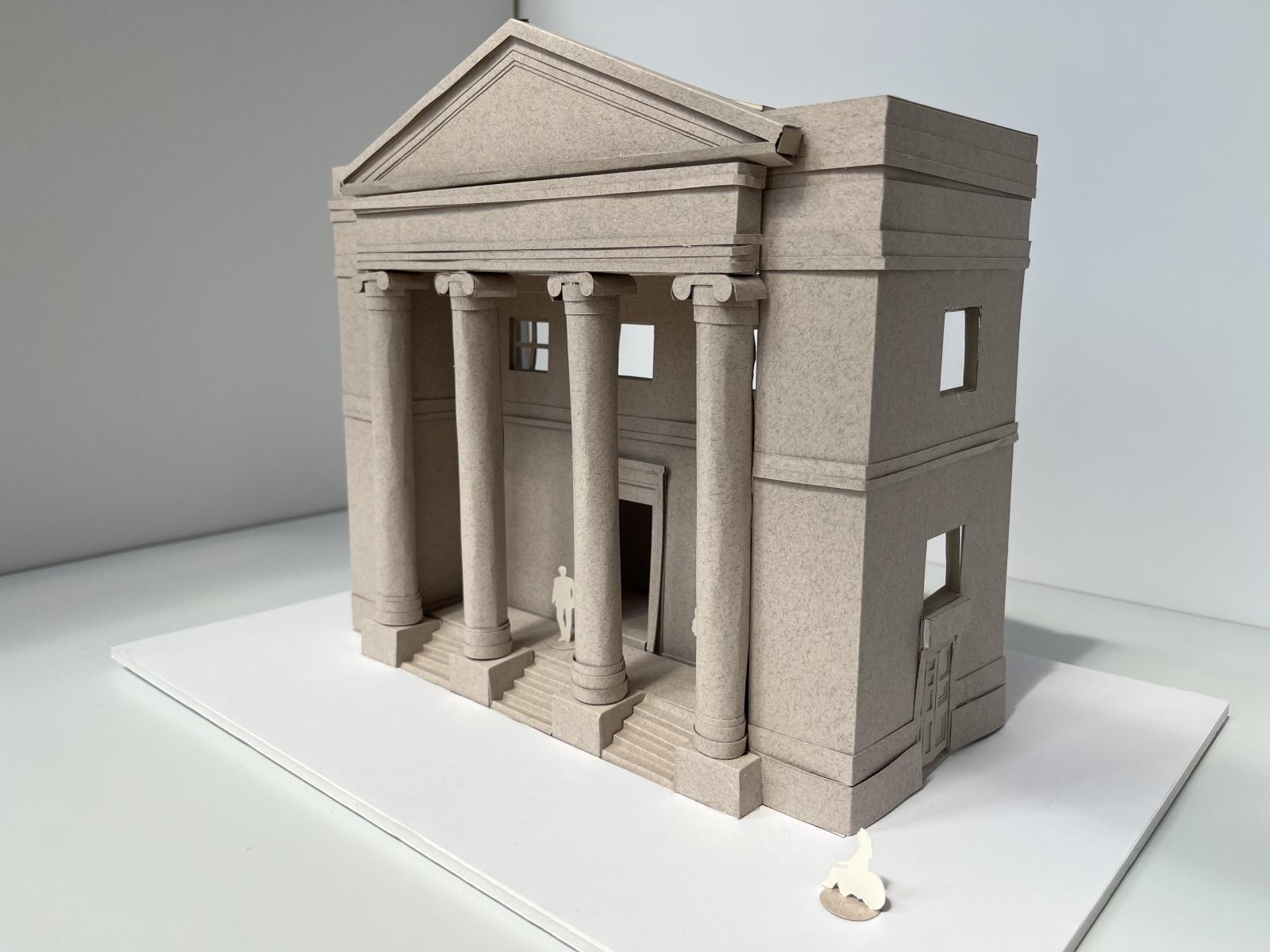 Portico Library, Manchester 1:50 Facade Model 
The model was produced at Bid Stage (RIBA Stage 0) to help secure the project and clearly communicate our vision for opening up the Listed Building to make it accessible to all.

A key move was the bold intervention of removing the portico steps and drawing the change in level into the vestibule. This strategy ensured that all visitors would enter through the same principal front door, reinforcing equality of access while maintaining the dignity of arrival.

Model making is more than representation; it is an essential part of the design process. It shapes ideas as much as it communicates them. This model enabled us to test the extent of the proposed step removal and understand the impact such an intervention would have on the historic fabric of the building.

The physical act of constructing and engaging with models provides a deeper spatial and material understanding, fostering critical and creative thinking. It exposes the logic — and potential shortcomings — of a design in ways that drawings alone cannot always reveal.

The model was created using the Cricut Maker Machine with paper, mount board, and book paper sheets. The external steps where removable to communicate the options available. 

Gemma Birchall, Associate Architect and Modelmaker. Project Team - John Piercy Holroyd, Tom Brigden